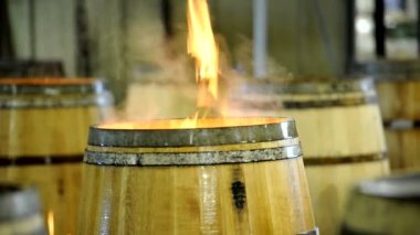 Odun fıçısından yükselen alevler ve insan şarap fıçısı üretimi için alevleri karıştırıyor.