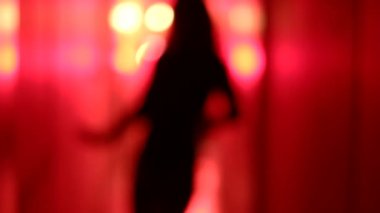 Bulanık, kırmızı koridorda dans seksi bir kadın silüeti.