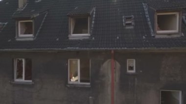 Almanya'nın Gladbeck kentinde terk edilmiş bir mahallenin havadan, alçak irtifauçuş yakın izleme çekim soldan sağa bir lens parlama ile biten evlerin eski bir satır önünde.