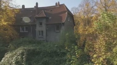 Kömür madenciliği kasaba Gladbeck terk edilmiş bir çeyrek andan, Almanya, düşük irtifa uçuş, orta izleme çekim sağdan sola eski bir evin önünde ve sarı sonbahar yaprakları ile büyük bir ağaç.