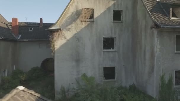 德国格拉德贝克煤矿小镇Gladbeck一个废弃的季度，在一排破旧的房屋前从右到左进行中跟踪拍摄，然后缓慢上升，从左到右在屋顶和烟囱上平移射击. — 图库视频影像