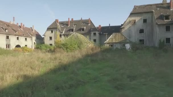 石炭鉱山の町グラッドベック、ドイツ、低高度、長い追跡は牧草地の上に前方に撮影し、ゆっくりと働く発電所と割り当て庭園で終わるみすぼらしい家の上に上昇する放棄された四半期の空中. — ストック動画