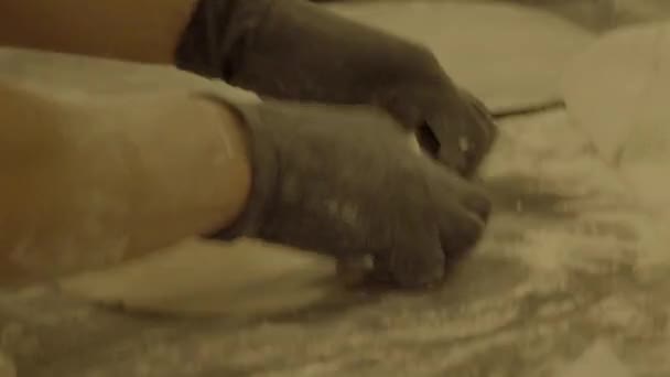 Vrouwelijke handen in handschoenen rollend deeg met een deegroller. Slog3, close-up. — Stockvideo