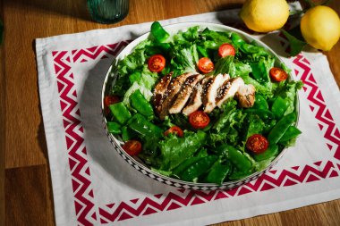Kızarmış tavuk salatası, yeşil marul, ızgara et, yeşil bezelye, domates, limon, taze ve sağlıklı Akdeniz usulü yemek.