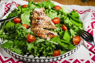 Kızarmış tavuk salatası, yeşil marul, ızgara et, yeşil bezelye, domates, limon, taze ve sağlıklı Akdeniz usulü yemek.