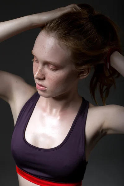 Mode portret van een jong meisje in een sport-top op een donkere achtergrond — Stockfoto