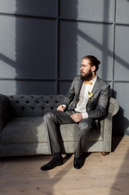 Yakışıklı güçlü, acımasız sakallı adam gri kanepede oturan