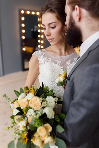 Portret van een mooie bruid met een boeket en de bruidegom met een baard — Stockfoto