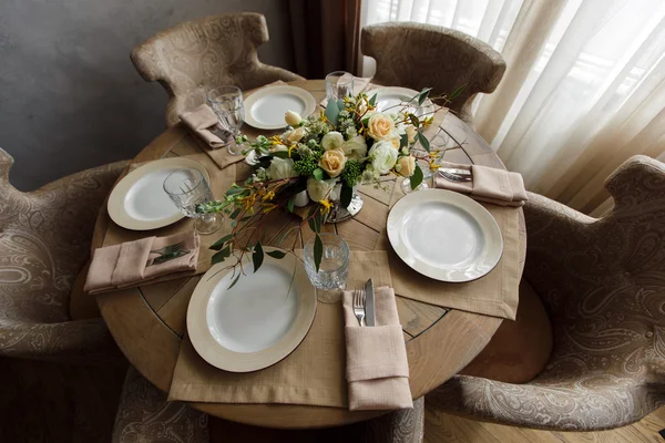 Round wooden dining table decorated with bouquet