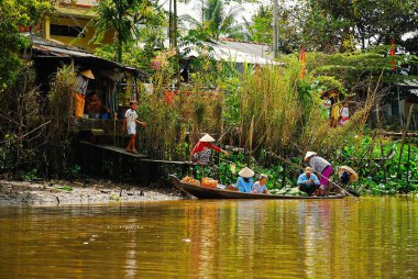 Geleneksel Vietnamlı aile Mekong nehri kıyısındaki evlerinin önünde.