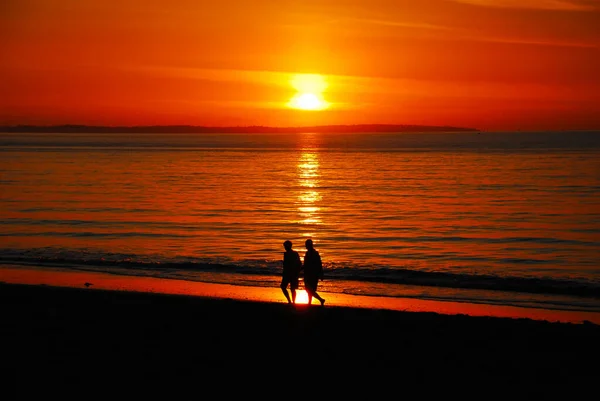 Paar geliefden wandelen 's avonds op het strand tijdens de romatische zonsondergang — Stockfoto