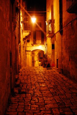 Eski Matera caddesinde, gece eski kasabada. Parlak lambalar ve taş döşeli evler arasında.