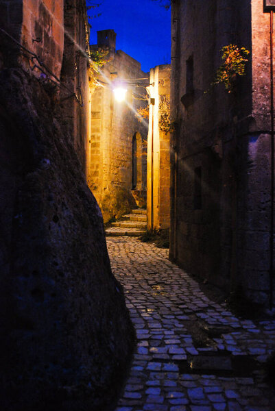 The Matera streets in the night with the typical stones houses and shining lamps on the evening