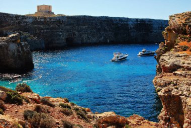 Maltese Comino Adası 'ndaki Blue Lagoon' un arka planında Saint Mary bataryası ve Redoubt var.
