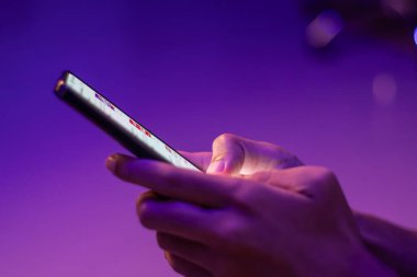 Karanlık odada neon ışıklı akıllı telefondan mesaj yazan bir adam. Sohbet ya da iletişim kavramı.