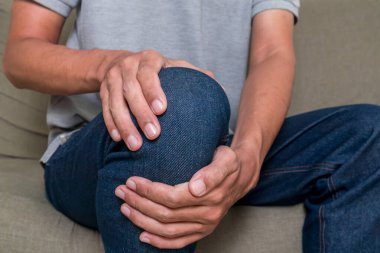 Genç adam ağrılı dizini tutuyor