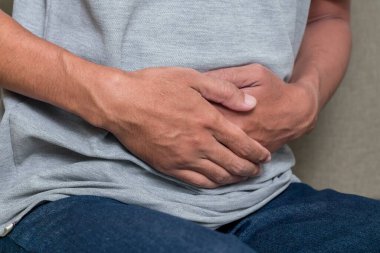 Genç adam acı içinde karnını tutuyor. Mide ağrısı, ishal, kabızlık ya da aç bir adam..