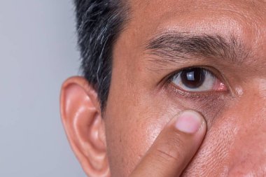 Asyalı bir adam gözlerini kontrol ediyor. Bir adamın açık gözlerinin yakın plan çekimi..