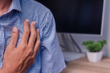 Sol göğsünde ağrı hisseden bir erkek işçi. Kalp krizi belirtileri.