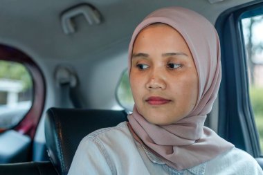 Müslüman kadın yolcu arka koltukta oturuyor.