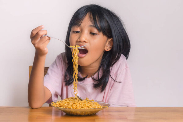 Маленькая девочка наслаждается тарелкой жареной лапши дома