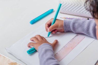 Masada kalem kullanmayı öğrenen küçük bir Asyalı kız.