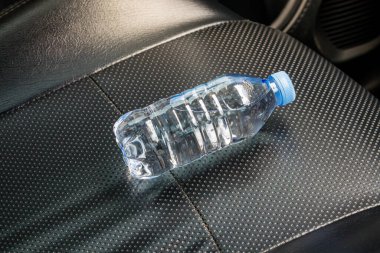 Araba koltuğunda güneş ışığına maruz kalmış bir su şişesi.