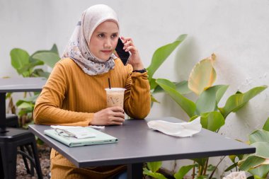 Endonezyalı Müslüman bir kadın akıllı telefonuyla arama yapıyor.