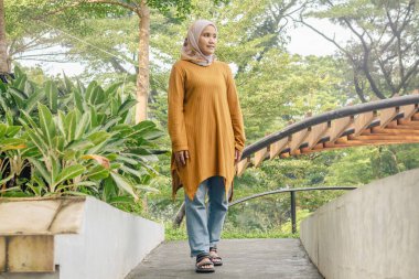 Endonezyalı Müslüman bir kadın parkta doğal atmosferin tadını çıkarırken yürüyor.