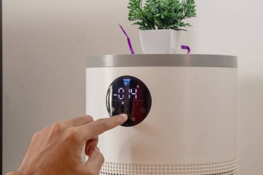 Evde erkek eli hava temizleyicinin düğmesine bas.