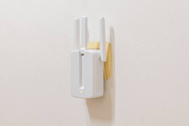 Bir duvar soketine üç anten takılı kablosuz ağ aralığı genişleticisi