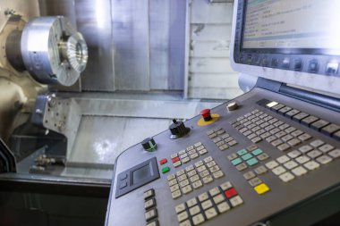 CNC makinesinin kontrol paneli, üretilen parçanın arka planına karşı