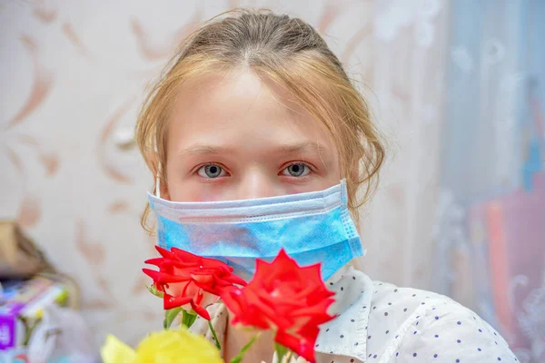 一名戴防护面具的女孩手持一束鲜花 嗅着玫瑰 在眼镜蛇 19病毒大流行期间被隔离 — 图库照片