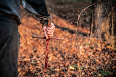 Bir adam elinde şeytanları kovmak için kanlı tahta bir haç tutuyor. Tanrı 'ya ibadet et ve kurban et.