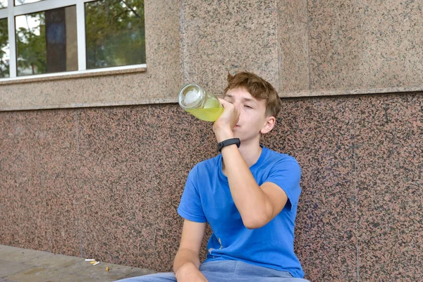 一个喝醉酒的少年乞丐坐在那里 手里拿着一杯饮料 乞求钱财 青少年酗酒概念 — 图库照片