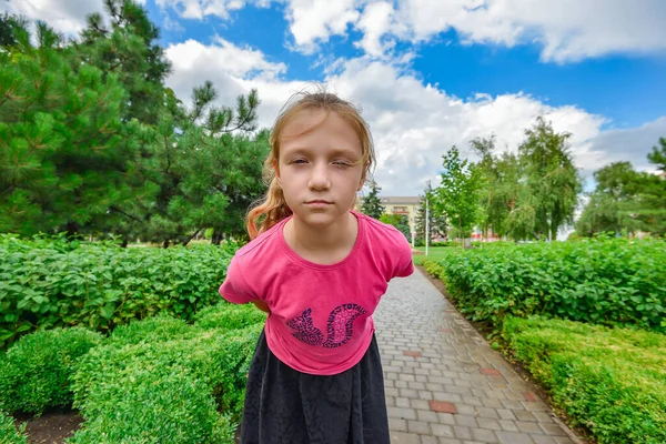 緑の葉の間の公園の感情的な女の子は 広角カメラを見て — ストック写真