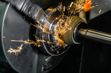 Silindirik bir öğütme makinesinde yüz aşındırıcı bir tekerlekle parçanın yüksek hassasiyetle bitişi.