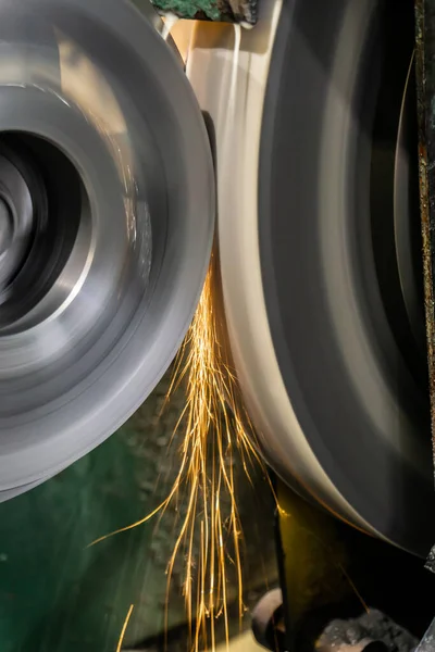 Grinding and processing a part on a grinding machine at a manufacturing enterprise, sparks from the abrasive fly in different directions.