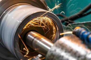 Bir imalat şirketinde öğütme makinesinin bir parçasını öğütmek ve işlemek, farklı yönlerdeki yıpratıcı sinekten kıvılcımlar saçar..