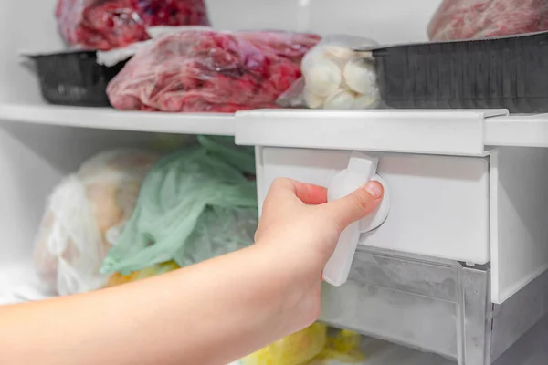 A Woman Opens an Ice Maker Tray in the Freezer To Take Ice Cubes