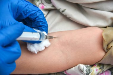 Doktor hasta bir çocuğa damardan iğne yapıyor..