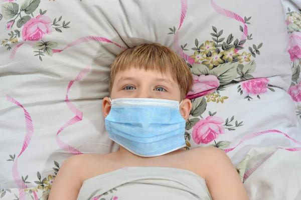 一个头戴口罩的病童躺在床上 — 图库照片