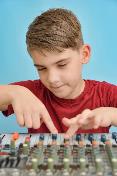 Stylish boy customizes the keys and buttons on the mixing console by winding fenders