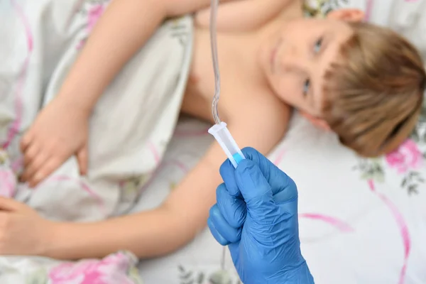 一个戴蓝色手套的医生为一个生病的孩子调整投药器 — 图库照片