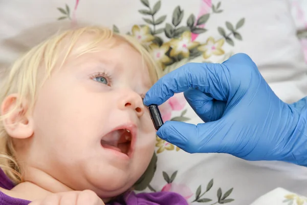 Médico Luvas Azuis Uma Criança Doente Uma Cápsula Preta Medicamento — Fotografia de Stock