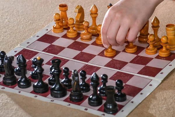 The player holds a white pawn in his hand and starts the game of chess.