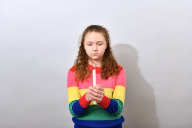 Kız elinde yanan bir mum tutuyor ve ona bakıyor..