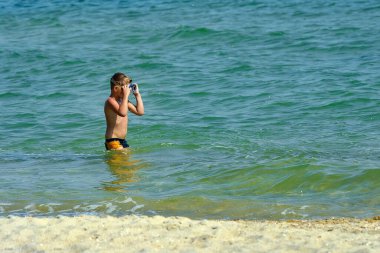 Dalış maskeli bir çocuk suyun altına dalıyor..