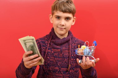 Çocuk bir elinde dolar, diğer elinde Paskalya yumurtası tutuyor..