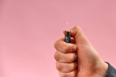 Pembe arka planda bir adamın elinde yanan çakmak..